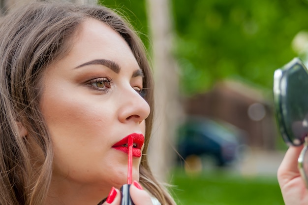 Mooie stijlvolle brunette vrouw correcte make-up. Portret van aantrekkelijke jonge vrouw. Leuke zakenvrouw aanpassen haar make-up op open lucht