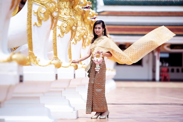 Mooie Thaise vrouw in Thais traditioneel kostuum bij tempel