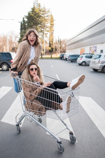 Mooie tieners poseren met winkelwagen