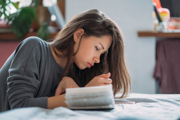 Mooie uitgeputte vrouwelijke student die voor aanstaand onderzoek voorbereidingen treft.