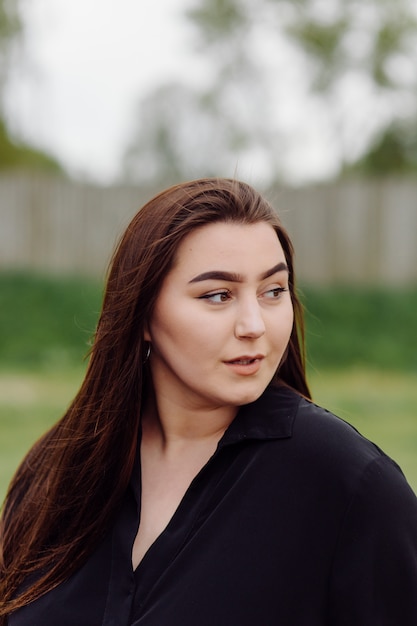 Mooie vriendschappelijke jonge vrouw met het bruine haar die van de schouderlengte in openlucht stellen