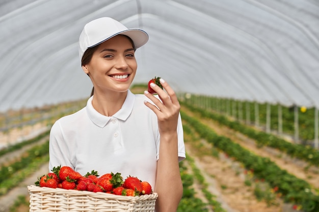 Mooie vrouw die aardbei snuift en bewondert