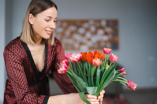 Mooie vrouw die bloemen schikt, gepresenteerd door haar man thuis, gelukkig en vreugdevol