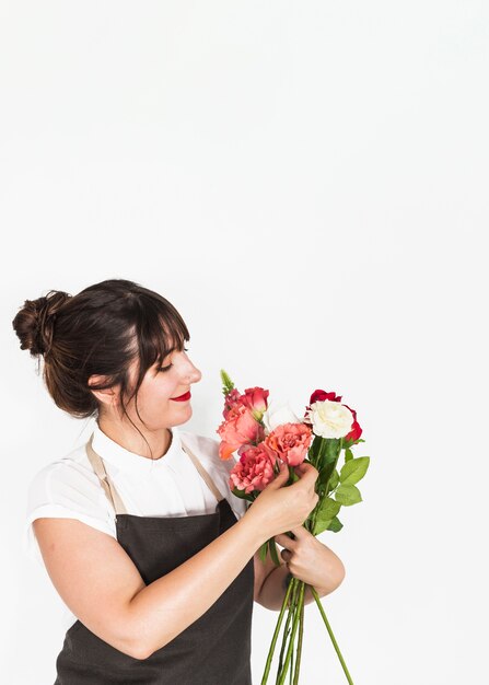 Mooie vrouw die bos van bloemen op witte achtergrond bekijkt