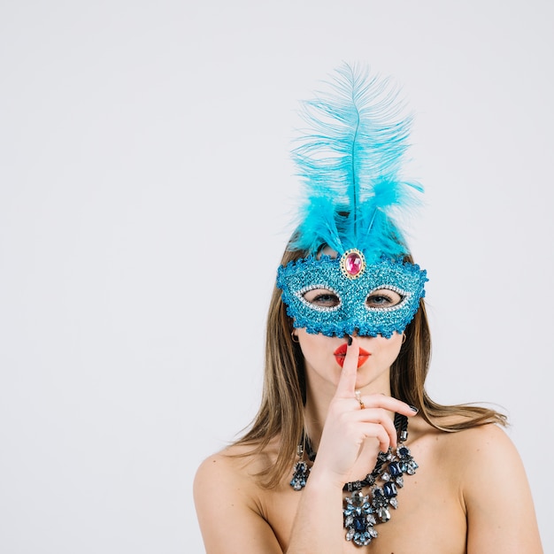 Mooie vrouw die Carnaval-masker met vinger op haar lippen draagt