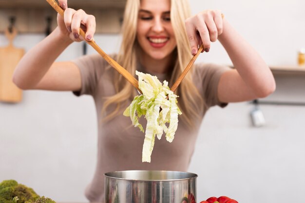 Mooie vrouw die de kom mengt met salade