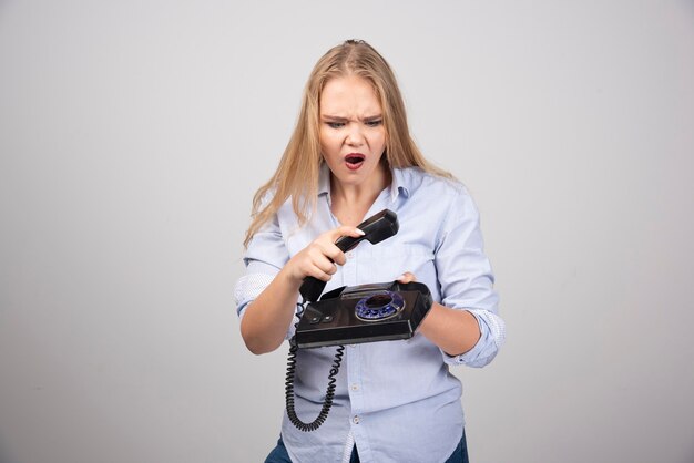 mooie vrouw die de telefoon ophangt isoleerde grijze muur.