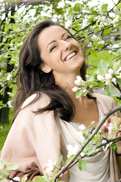 Mooie vrouw die door tot bloei komende boom lacht