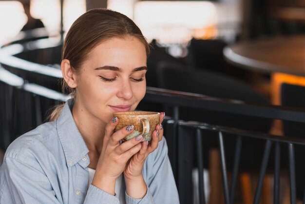 Mooie vrouw die een kop thee ruikt