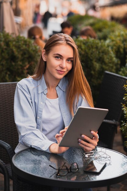 Mooie vrouw die een tablet houdt en op fotograaf kijkt