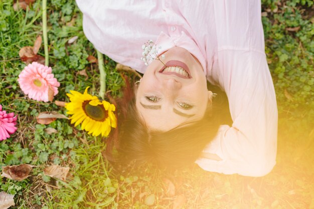 Mooie vrouw die en op gras glimlacht ligt