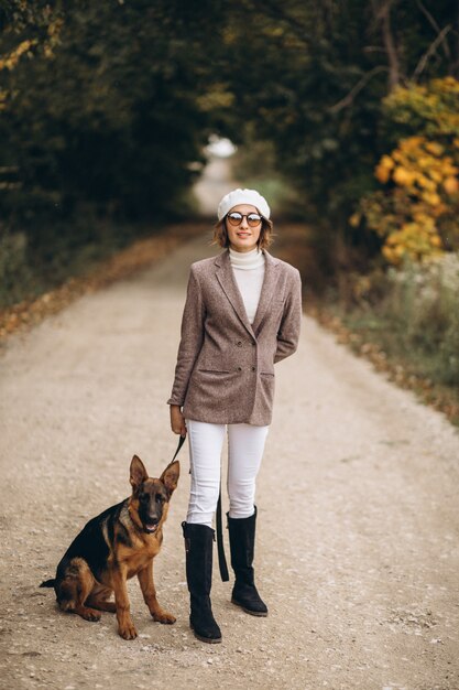 Mooie vrouw die haar hond in de herfstpark opstapt