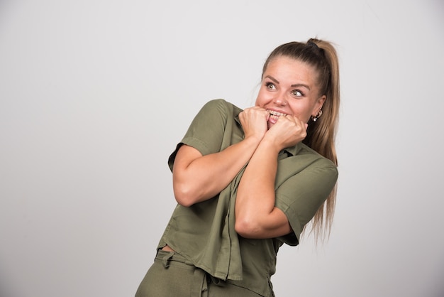 Mooie vrouw die haar kant op grijze muur bekijkt.