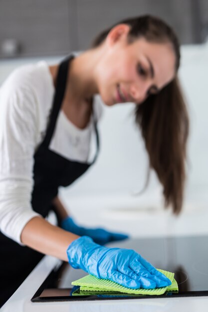 Mooie vrouw die het huishoudelijk werk doet terwijl het schoonmaken in de keuken