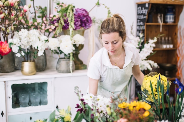 Gratis foto mooie vrouw die in bloemwinkel werkt