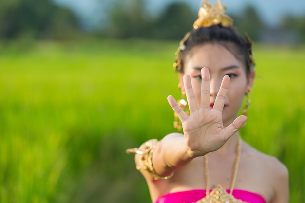 Mooie vrouw die in Thaise traditionele uitrusting en zich bij tempel glimlacht bevindt