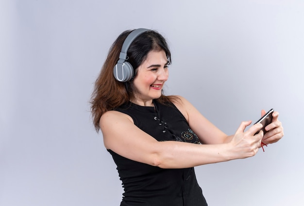 Mooie vrouw die in zwarte blouse selfie in hoofdtelefoons maakt