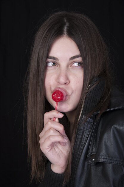 Mooie vrouw die lolly in zwarte jas eet