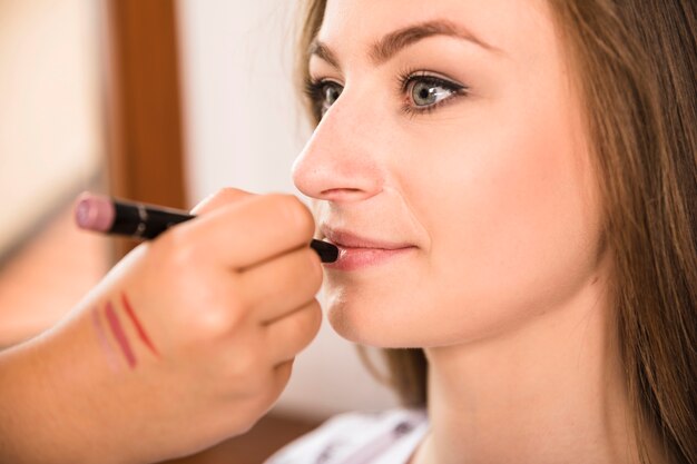 Mooie vrouw die make-up van kunstenaar ontvangt