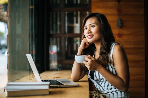 Mooie vrouw die met laptop computer bij koffiewinkelkoffie werkt