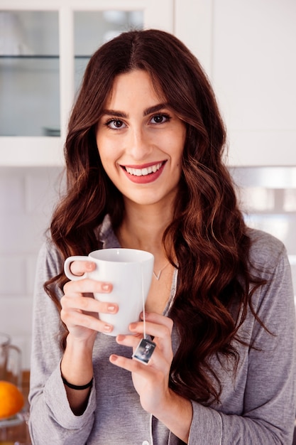 Mooie vrouw die met mok camera bekijkt