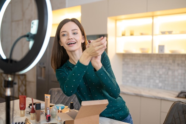 Mooie vrouw die nieuwe cosmetica demonstreert en er betrokken uitziet