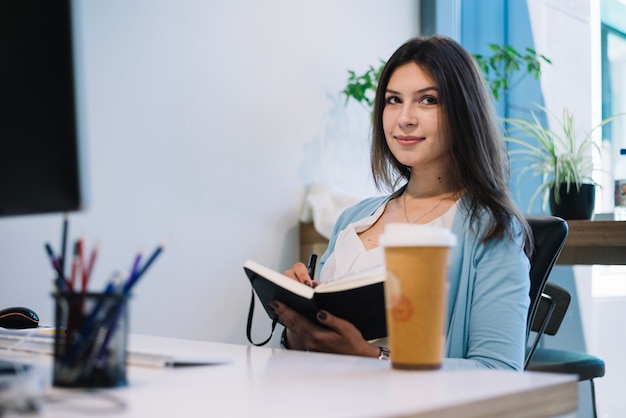 Mooie vrouw die nota&#39;s in notitieboekje maakt