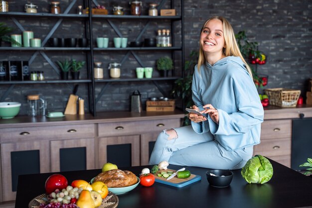 Mooie vrouw die op de mobiele telefoon in keuken thuis spreekt