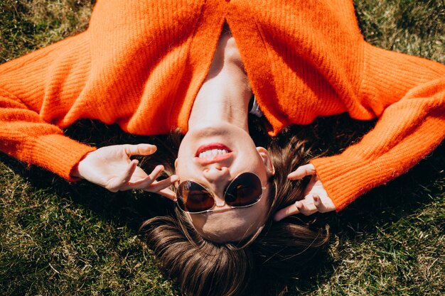 Mooie vrouw die op gras in een kleurrijke sweater ligt