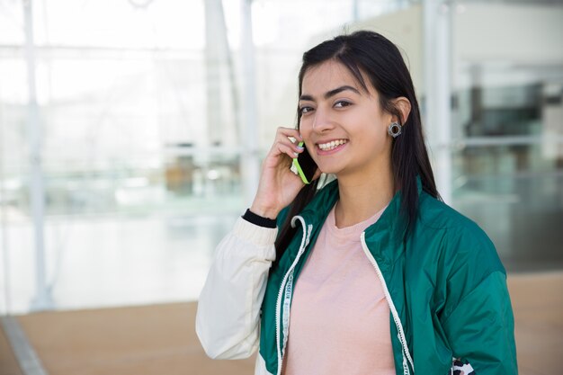 Mooie vrouw die op telefoon spreekt, die camera, het glimlachen bekijkt