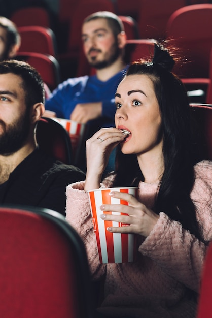 Mooie vrouw die popcorn in bioskoop eet