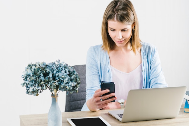 Mooie vrouw die smartphone in bureau gebruikt