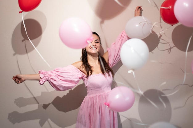 Mooie vrouw die Valentijnsdag viert in een roze jurk met ballonnen