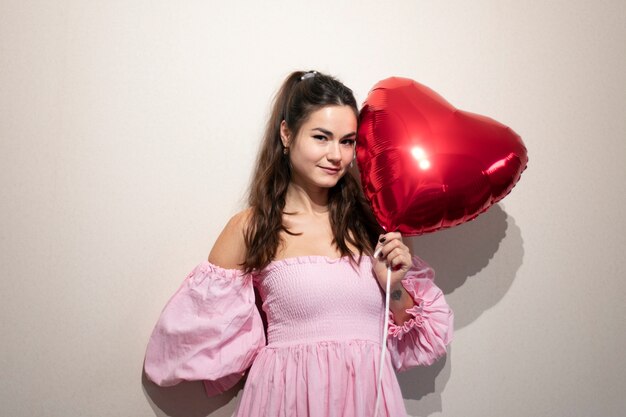 Mooie vrouw die Valentijnsdag viert in een roze jurk met ballonnen