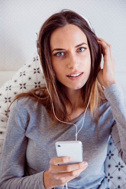 Mooie vrouw die van muziek in bed geniet