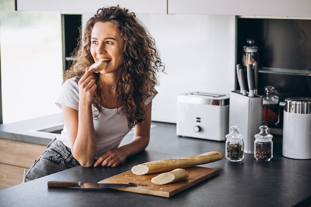 Gratis foto mooie vrouw die vers brood eet bij de keuken