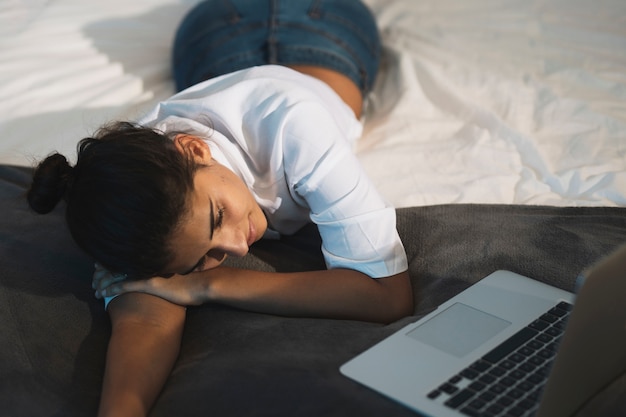 Mooie vrouw die voor laptop rust