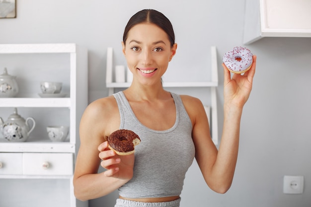 Mooie vrouw die zich in een keuken met doughnut bevindt