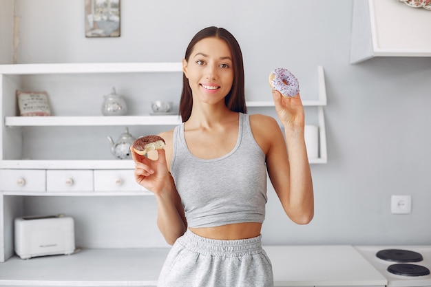 Mooie vrouw die zich in een keuken met doughnut bevindt