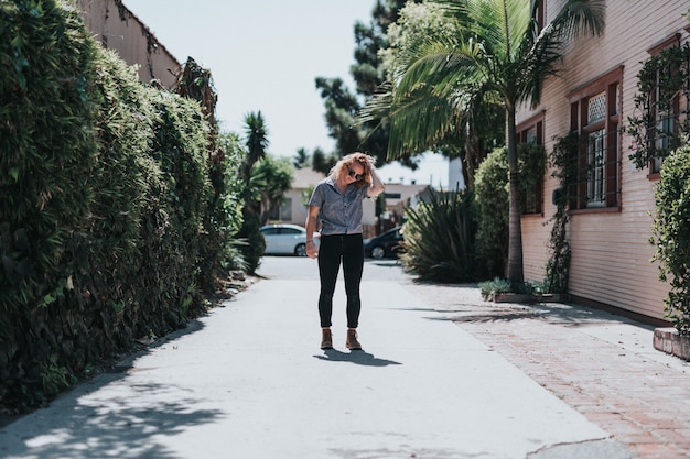 Mooie vrouw die zich op een lege weg bevindt die haar haar bevestigt