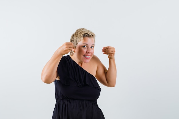 Mooie vrouw die zich voordeed als iets in zwarte blouse vast te houden