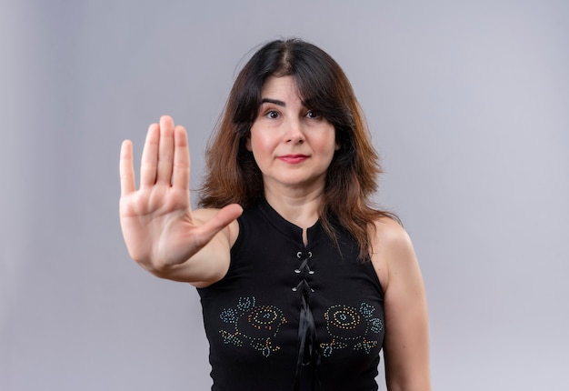 Mooie vrouw die zwarte blouse draagt die stopbord met de rechterhand toont