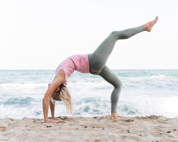 Gratis foto mooie vrouw doet yoga op het strand