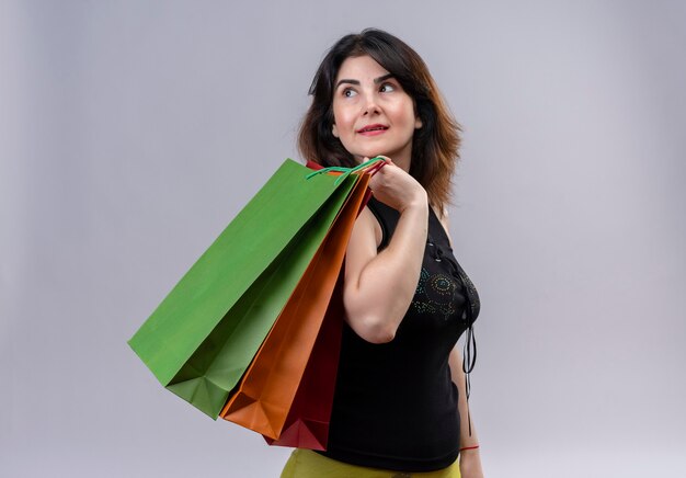 Mooie vrouw, gekleed in zwarte blouse op zoek statig met boodschappentassen