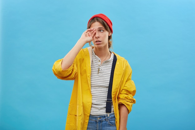 Mooie vrouw haar ogen wrijven op zoek moe na gaan vissen met haar man voor de hele nacht willen slapen geïsoleerd op blauwe muur. vrouw gekleed terloops met slapeloze uitdrukking