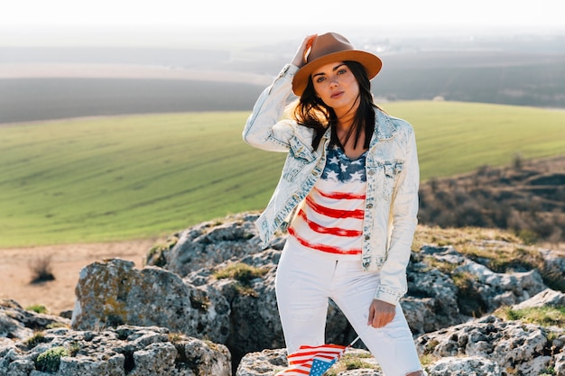 Mooie vrouw in Amerikaanse vlag t-shirt poseren op de top van de berg