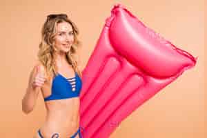 Gratis foto mooie vrouw in blauwe bikini met roze matras