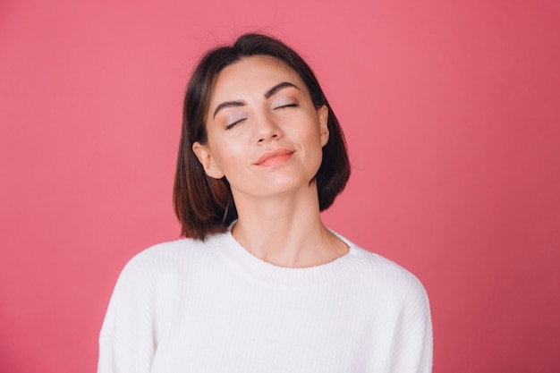 Mooie vrouw in casual witte trui, geïsoleerde staande kalm gezicht gesloten ogen schattige glimlach