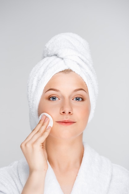 Mooie vrouw in de make-up van de badjasstart met spons