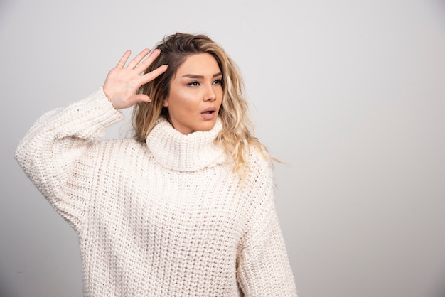 Mooie vrouw in de wintersweater die haar hand toont.